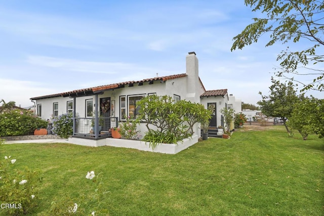 view of front of property with a front lawn, a tiled roof, stucco siding, and a chimney