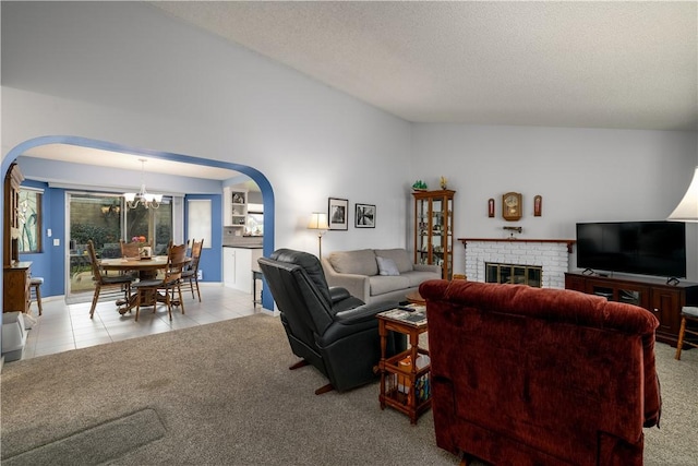 carpeted living room with tile patterned flooring, a fireplace, arched walkways, a notable chandelier, and a textured ceiling