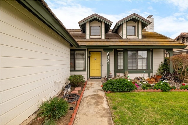 doorway to property with a yard and a tile roof