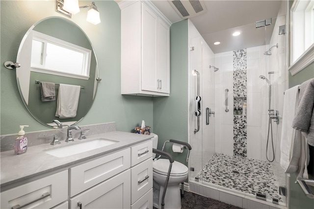 bathroom with vanity, toilet, visible vents, and a stall shower