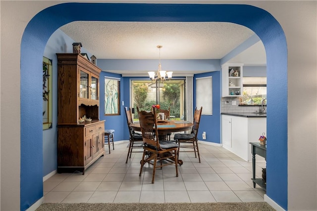 dining room featuring light tile patterned floors, a notable chandelier, a textured ceiling, and baseboards