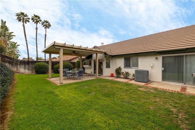 back of house with central AC, a lawn, stucco siding, a fenced backyard, and a patio area