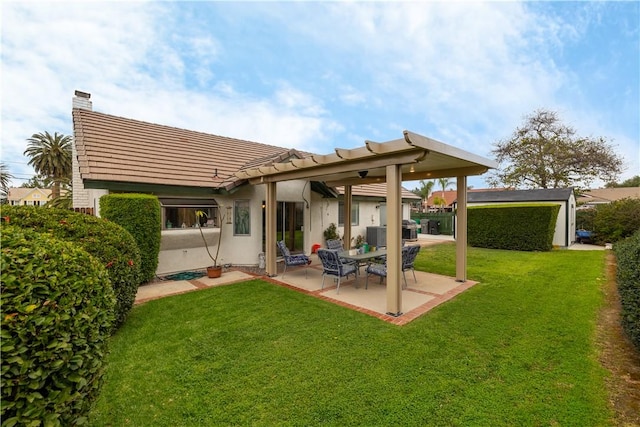 back of house featuring a patio, stucco siding, a chimney, a tile roof, and a lawn