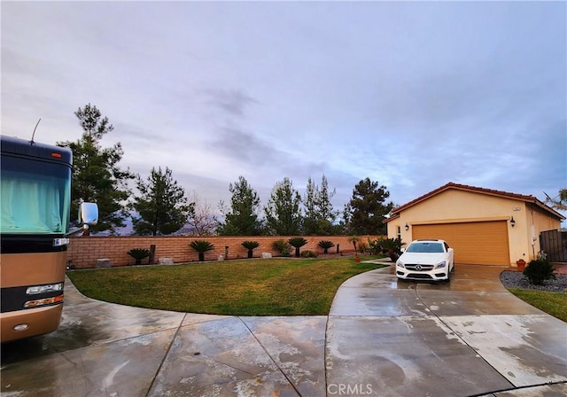 view of yard featuring an outbuilding, driveway, a garage, and fence