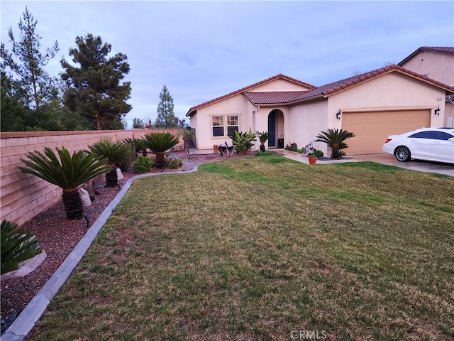 mediterranean / spanish-style house featuring fence, driveway, an attached garage, stucco siding, and a front lawn