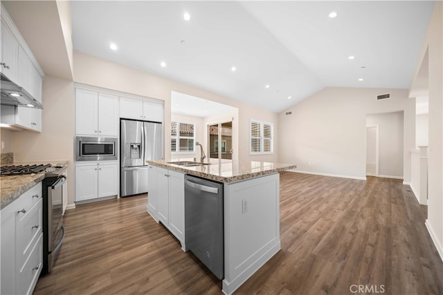 kitchen featuring visible vents, a kitchen island with sink, a sink, stainless steel appliances, and wall chimney range hood