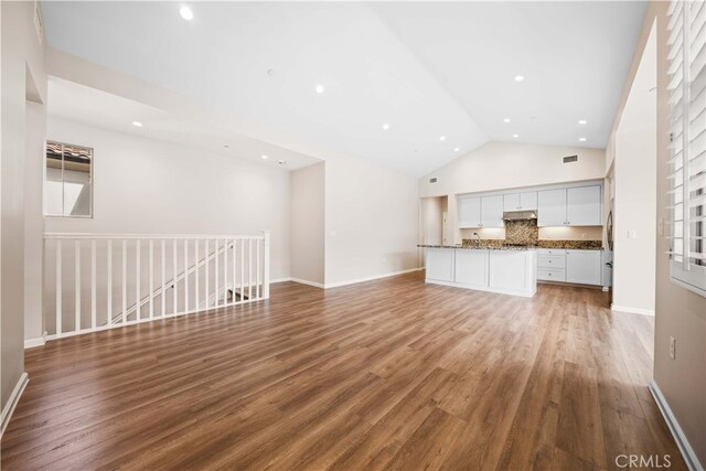 unfurnished living room featuring baseboards, high vaulted ceiling, and light wood-style flooring