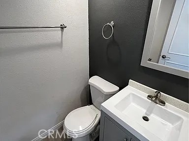 bathroom featuring toilet, vanity, and a textured wall