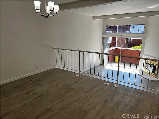 unfurnished room with beam ceiling, a chandelier, dark wood-type flooring, and baseboards