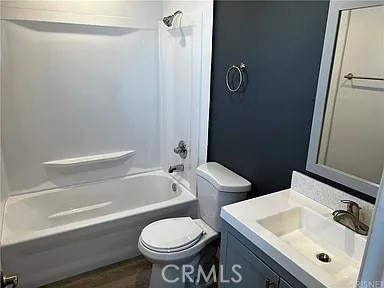 full bathroom with tub / shower combination, toilet, vanity, and wood finished floors