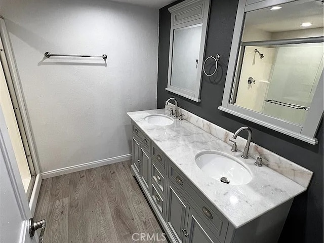 bathroom featuring double vanity, wood finished floors, baseboards, and a sink