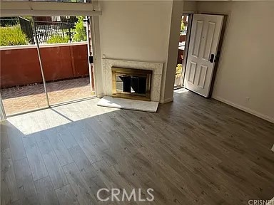 unfurnished living room featuring baseboards, wood finished floors, and a glass covered fireplace