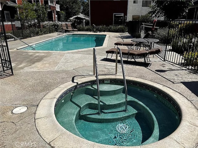 community pool with a community hot tub, a patio area, and fence