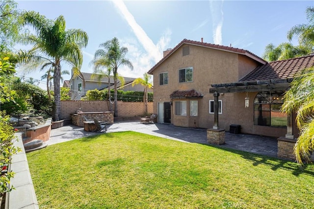 rear view of property featuring stucco siding, a lawn, a tile roof, a patio, and fence