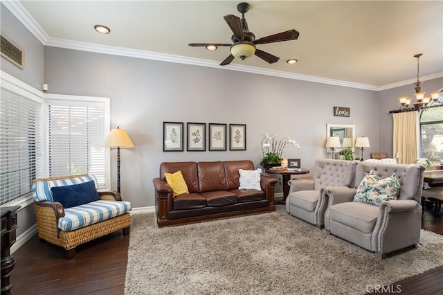 living area featuring wood finished floors, visible vents, baseboards, ornamental molding, and ceiling fan with notable chandelier