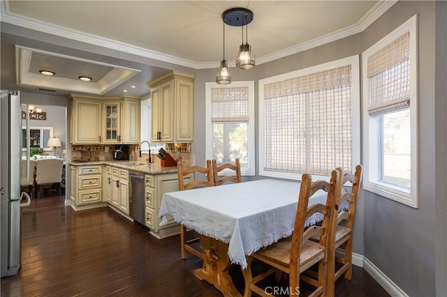 dining room featuring dark wood finished floors, a raised ceiling, baseboards, and ornamental molding