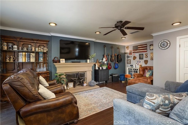 living area with a fireplace with raised hearth, ornamental molding, wood finished floors, and ceiling fan