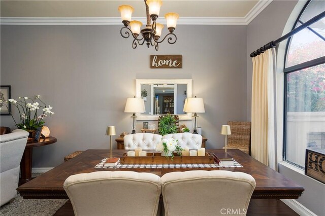 dining room featuring a notable chandelier, crown molding, baseboards, and wood finished floors