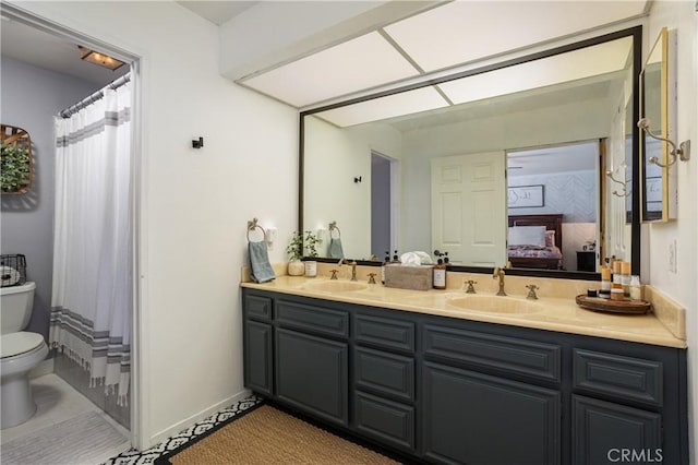 ensuite bathroom featuring a sink, connected bathroom, toilet, and double vanity