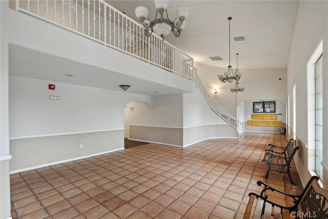 interior space with baseboards, a chandelier, stairs, a high ceiling, and arched walkways