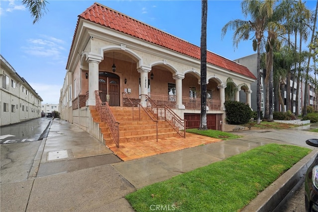 view of front of property featuring stucco siding, covered porch, and a tile roof