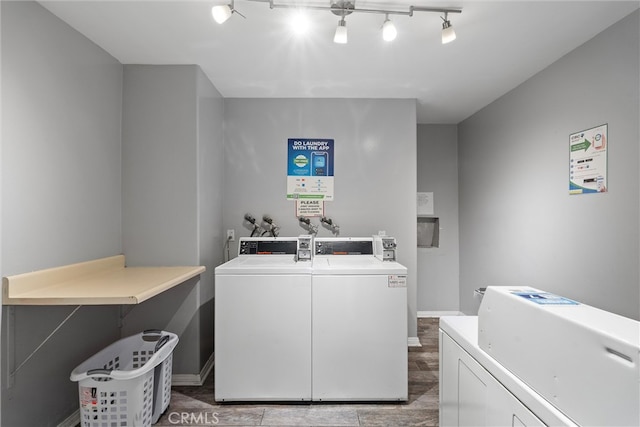 community laundry room with independent washer and dryer, rail lighting, and baseboards