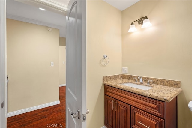 bathroom with baseboards, toilet, wood finished floors, and vanity