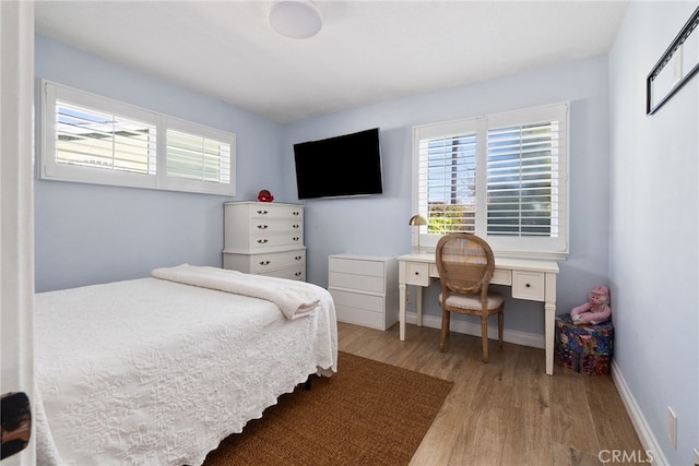 bedroom featuring baseboards, multiple windows, and wood finished floors