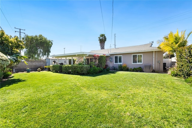 rear view of property with stucco siding, a lawn, and fence