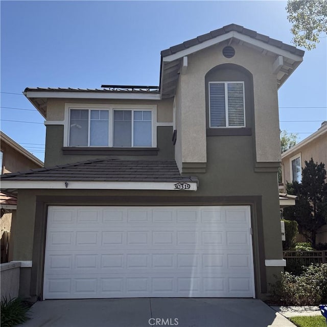 traditional home featuring a tiled roof, a garage, driveway, and stucco siding