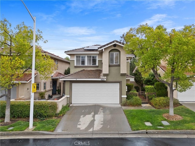 view of front facade featuring fence, a tiled roof, concrete driveway, solar panels, and stucco siding