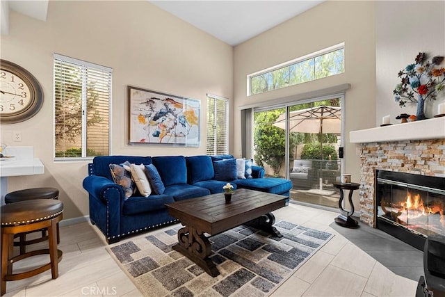 living area featuring baseboards, a fireplace, and a towering ceiling
