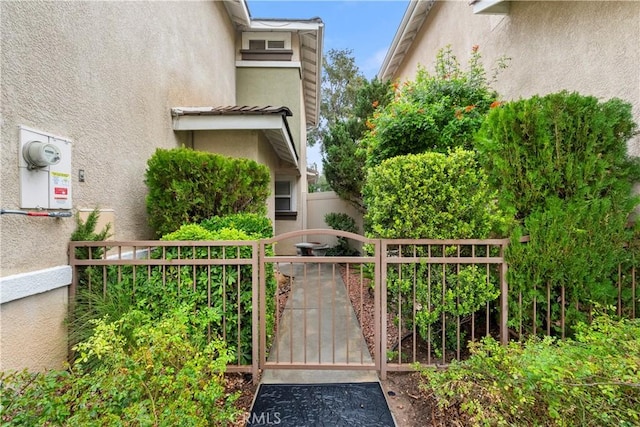 view of side of home with a gate, fence, and stucco siding