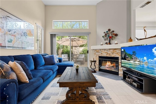 living room with visible vents, a high ceiling, and a fireplace