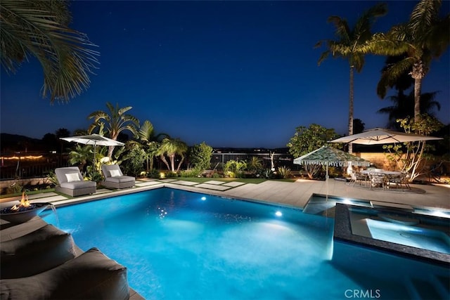 pool at twilight with a patio, a pool with connected hot tub, a grill, and fence