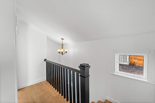 stairway featuring wood finished floors, baseboards, and a chandelier