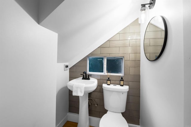 half bath featuring tile walls and toilet