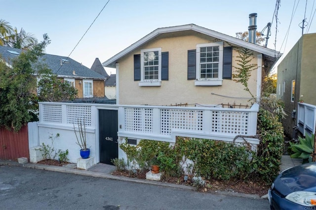 view of front facade with stucco siding and fence