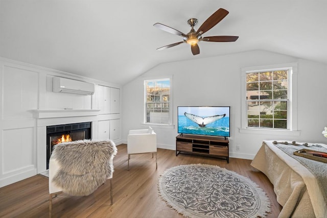 living room with lofted ceiling, wood finished floors, a lit fireplace, and a wall mounted AC