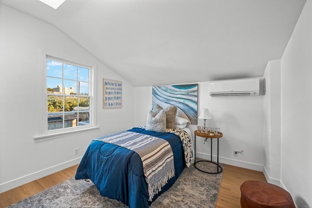 bedroom with a wall unit AC, wood finished floors, baseboards, and vaulted ceiling