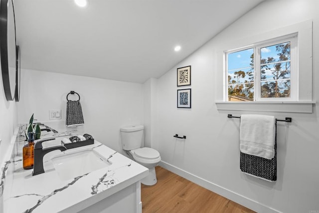 bathroom featuring toilet, lofted ceiling, wood finished floors, baseboards, and vanity