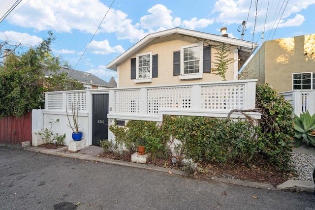 view of side of home featuring stucco siding and fence