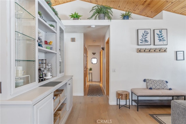 corridor featuring baseboards, wood ceiling, light wood-style flooring, and vaulted ceiling