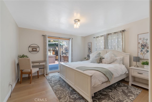 bedroom featuring light wood-style flooring, baseboards, and access to outside