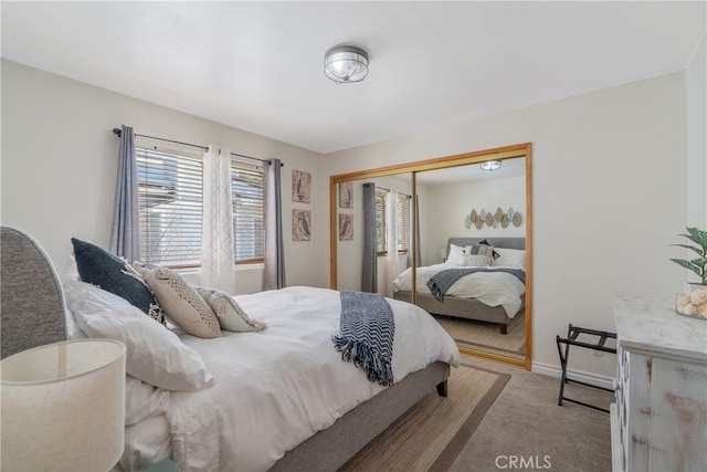 carpeted bedroom with a closet and baseboards