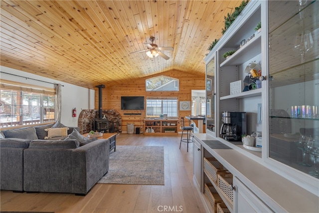 living room featuring hardwood / wood-style floors, a wood stove, vaulted ceiling, wood walls, and wooden ceiling