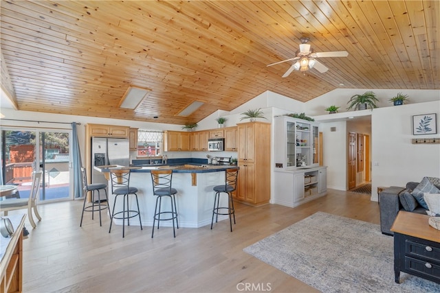 kitchen with a breakfast bar, light wood finished floors, stainless steel appliances, and a ceiling fan