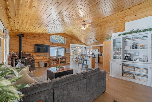 living room with wooden ceiling, a wood stove, light wood finished floors, and wood walls