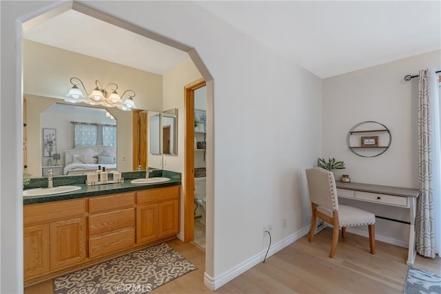 bathroom with a sink, double vanity, wood finished floors, and ensuite bathroom