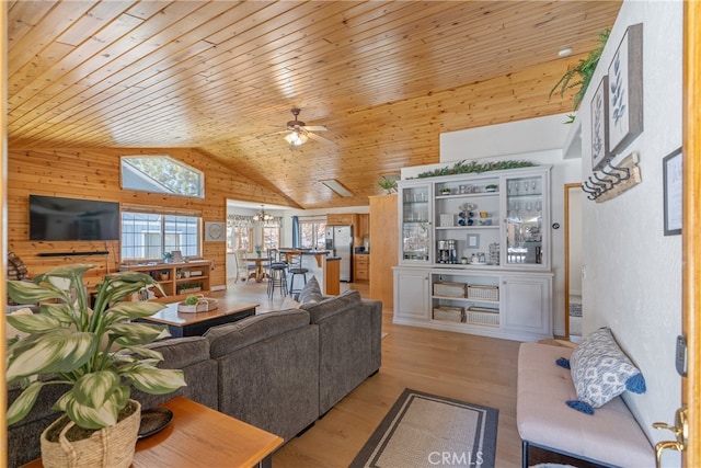 living area with ceiling fan with notable chandelier, wooden ceiling, wooden walls, and light wood-style floors